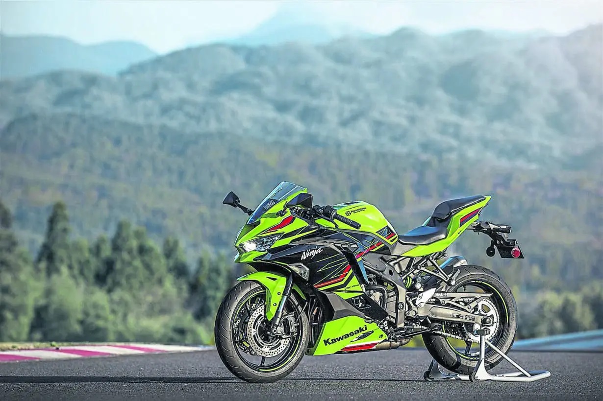 Kawasaki sport bike on a dry B-road, both tyres loaded.